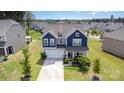 Aerial view of a two-story home with a manicured lawn and a beautiful neighborhood at 205 Falls Cove Dr, Troutman, NC 28166