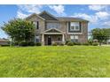 Charming two-story gray brick home with a manicured lawn and lush landscaping at 410 Alucio Ct, Matthews, NC 28104
