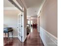Elegant hallway with hardwood floors, white wainscoting, and a view of the living spaces at 5797 Mcclintock Dr, Denver, NC 28037