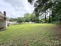 Expansive backyard with lush lawn, mature trees, and a partially fenced perimeter, perfect for outdoor activities at 6539 Louglen Cir, Charlotte, NC 28212