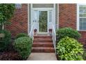 Inviting brick entrance with stairs, potted plants, and sidelights, showcasing a warm arrival at 10043 Elsenham Ln, Charlotte, NC 28269