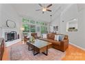 Bright living room featuring a fireplace, large windows, vaulted ceilings, and comfortable leather furniture at 10043 Elsenham Ln, Charlotte, NC 28269