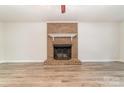 Bright living room featuring a classic brick fireplace and modern, light wood flooring, creating a cozy atmosphere at 10606 Danesway Ln, Cornelius, NC 28031