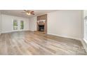 Bright living room showcasing a brick fireplace, light wood flooring, and access to the backyard through French doors at 10606 Danesway Ln, Cornelius, NC 28031