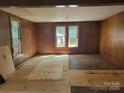 Spacious living room with wood-paneled walls and large windows, ready for renovation at 275 Hiddenite Church Rd, Hiddenite, NC 28636