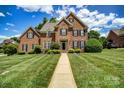 Classic brick home featuring manicured front yard with lush landscaping and a walkway to the front door at 4312 Beech Wood Ct # 140, Belmont, NC 28012