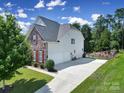 View of back and side of home featuring a long driveway, 3 car garage and fenced landscaping at 510 Placid Ct, Tega Cay, SC 29708