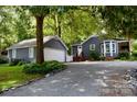 View of the home and detached garage showcasing the gravel drive, tree coverage, and cozy property at 5916 Indian Brook Dr, Matthews, NC 28104