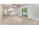 Spacious living room featuring neutral carpet, sliding glass doors, and view of an open kitchen through white decorative column at 7008 Wannamaker Ln, Charlotte, NC 28226
