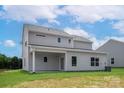 Back exterior of home features a covered patio, gray siding, and a spacious yard, perfect for outdoor entertaining at 7311 Jerimoth Dr, Charlotte, NC 28215