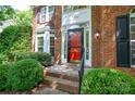 Inviting brick home entrance featuring a red door, decorative windows, and manicured greenery at 7321 Harrisonwoods Pl, Charlotte, NC 28270