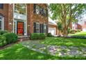 Beautiful brick home featuring well-manicured landscaping and a striking red front door at 7321 Harrisonwoods Pl, Charlotte, NC 28270