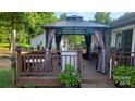 A deck with a gazebo, outdoor seating, and lovely greenery to create an inviting entertainment space at 7401 Merrily Ln, Charlotte, NC 28214