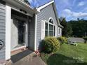 A view of the charming single story home highlighting the front door, beautiful landscaping and a picnic table at 7401 Merrily Ln, Charlotte, NC 28214