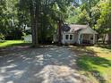 Inviting one-story home featuring a cozy front porch and a spacious gravel driveway surrounded by mature trees at 917 Tennyson Dr, Charlotte, NC 28208