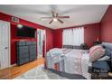 Cozy bedroom with red walls, wood floors, a ceiling fan, and an ensuite bathroom at 10925 Lassen Ct, Charlotte, NC 28214