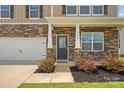 Close up of a charming home featuring stone accents, a two-car garage, and a well-manicured front lawn at 128 Cherry Birch St, Mooresville, NC 28117