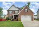 Charming two-story brick home featuring an attached two-car garage, well-manicured lawn, and a welcoming front garden at 1308 Stonewyck Dr, Salisbury, NC 28146