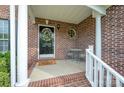 Inviting front porch with brick columns, a decorative wreath on the front door, and seating for relaxing outdoors at 1308 Stonewyck Dr, Salisbury, NC 28146