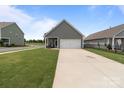 View of a well-maintained backyard and a two-car garage with a concrete driveway at 146 Kerri Dawn Ln, Locust, NC 28097