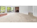 Open-concept living room with large windows and a brick fireplace feature at 1604 Sharon W Rd, Charlotte, NC 28210