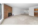 Spacious living room with a cozy brick fireplace and neutral carpet at 1604 Sharon W Rd, Charlotte, NC 28210
