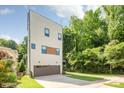 Modern three-story townhouse with a neutral facade and an attached garage featuring a lengthy driveway at 327 S Turner Ave, Charlotte, NC 28208