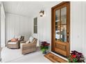 Close-up of a cozy front porch with wicker chairs and a wooden door at 416 Plantation Way # 3, Mount Gilead, NC 27306