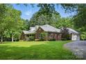 A beautiful brick home featuring a lush lawn, mature trees, and a charming side-entry garage at 4824 Waxhaw Farms Rd, Waxhaw, NC 28173