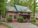 Charming log cabin featuring a metal roof with skylights, stone chimney, and gravel driveway at 5109 Walnut Grove Ln, Charlotte, NC 28227