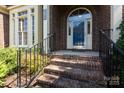 Inviting brick entryway with iron railings, leading to an arched doorway and prominent street number display at 6507 Fairway Point Dr, Charlotte, NC 28269