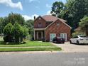 Brick home showcasing a well-manicured lawn, covered entry, and driveway parking at 7318 Brighton Brook Dr, Charlotte, NC 28212