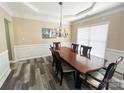 Elegant dining room with wainscoting, modern chandelier, and wood-look flooring at 9792 Ravenscroft Nw Ln, Concord, NC 28027