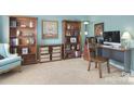 This home office features carpet, multiple bookshelves, and a cozy chair at 9792 Ravenscroft Nw Ln, Concord, NC 28027