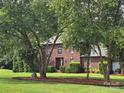 Beautiful brick home with a well-maintained lawn, mature trees, and brick-lined garden beds at 103 Northchase Dr, Concord, NC 28027