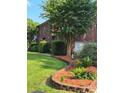 Brick home with landscaped yard featuring beautiful flowers, shrubs, and manicured lawn at 103 Northchase Dr, Concord, NC 28027