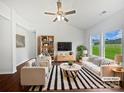 Bright, staged living room with white sofas, a striped rug, and large windows overlooking the backyard at 10328 Kempsford Dr, Charlotte, NC 28262