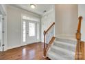 Bright foyer with gleaming hardwood floors, stairway with carpeted steps and decorative railing at 169 Halifax Dr, Fort Mill, SC 29707