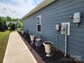 Landscaped side yard with potted plants, walkway, and a view of the fenced backyard at 195 Willow Valley Dr, Mooresville, NC 28115