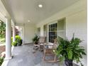 Relaxing front porch features slate tile, potted ferns, rocking chairs, and stately white columns at 2636 Chilton Pl, Charlotte, NC 28207