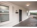 Inviting covered front porch with gray stained wood decking, and white painted wood walls and trim at 601 N Johnson St, Monroe, NC 28112