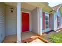 Close-up of the front door with red finish, sidelight, and classic exterior lighting at 676 Rebecca Jane Dr, Mooresville, NC 28115