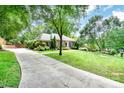 Brick home with a long driveway, mature trees and a beautifully landscaped lawn with manicured garden beds at 935 Trentle Ct, Charlotte, NC 28211