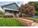Charming blue home featuring a welcoming porch, brick accents, an orange front door, and a beautiful flowering tree at 1008 Vanizer St, Charlotte, NC 28208