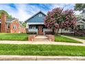 Charming blue home featuring a welcoming porch, brick accents, an orange front door, and a beautiful flowering tree at 1008 Vanizer St, Charlotte, NC 28208