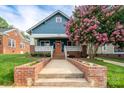 Charming blue home featuring a welcoming porch, brick accents, an orange front door, and a beautiful flowering tree at 1008 Vanizer St, Charlotte, NC 28208