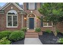 Close-up of the front entrance with arched windows and lush landscaping at 116 Ivy Hollow Ln, Mooresville, NC 28117