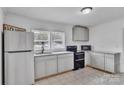 Bright kitchen features white cabinets, granite countertops, stainless steel refrigerator, and black range at 123 E Farmview St, Gastonia, NC 28054