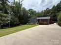 A one-story home with an extra long driveway and red shutters, set amongst lush green trees at 200 Breslin St, Wadesboro, NC 28170