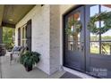 Cozy front porch features a seating area, brick facade, dark shutters, and an inviting entryway at 2122 Goose Creek Farm Ln, Indian Trail, NC 28079